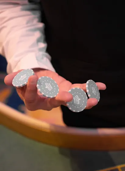 A dealer fanning four crown-marked chips across an open palm
