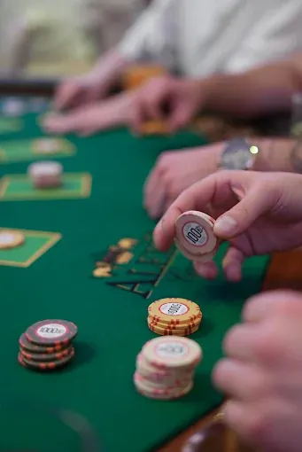 A hand resting on chips at the poker table