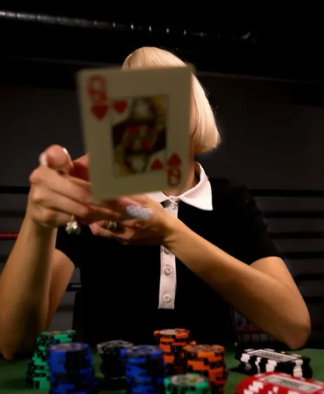 A dealer holding the queen of hearts up in front of her face