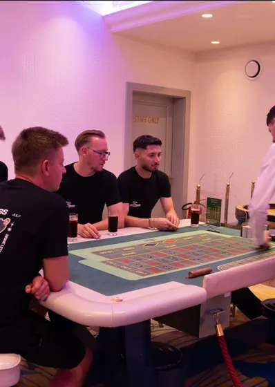 A group of guests standing around the roulette table