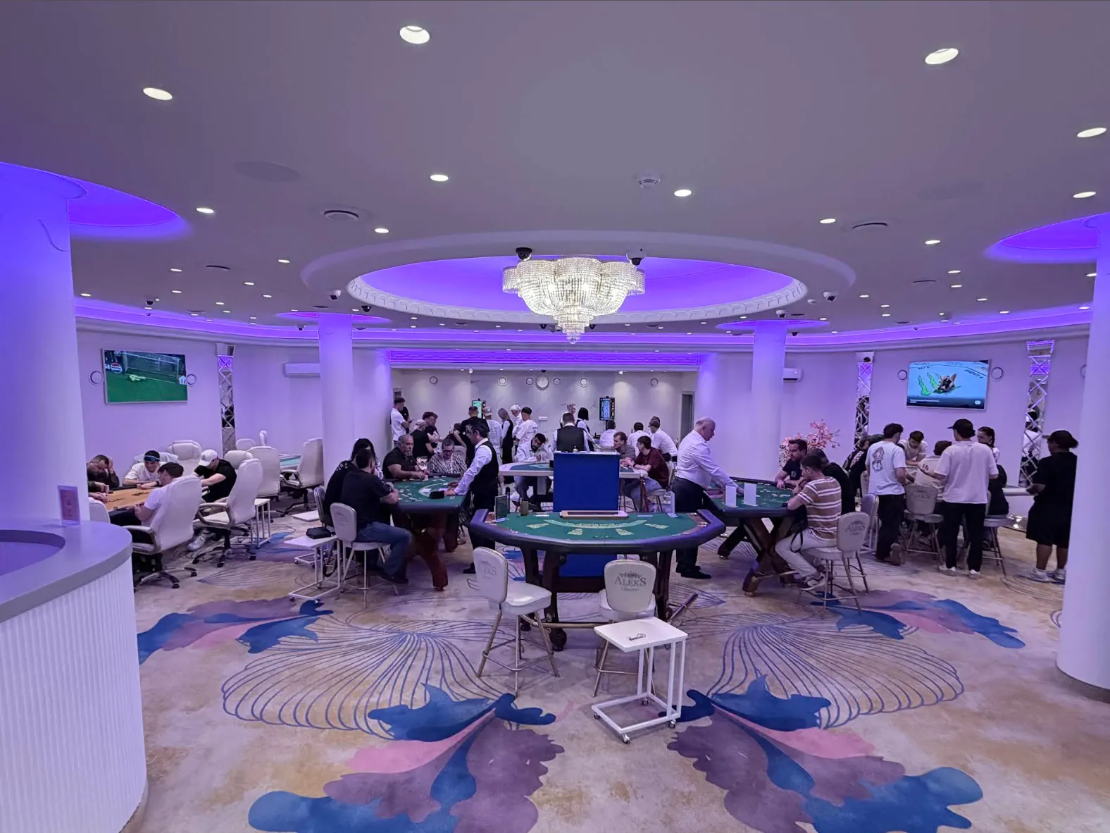 The live table floor, busy with players and dealers under the chandelier
